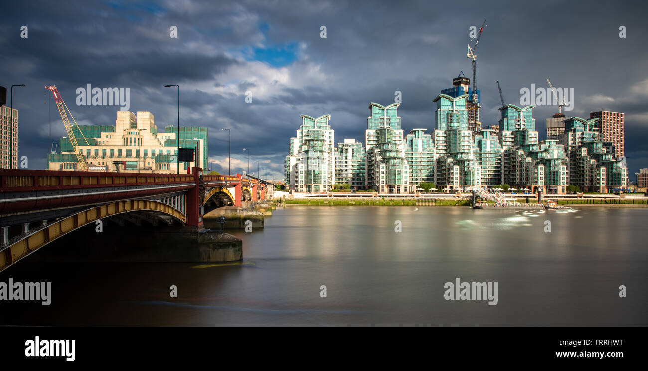 London, England, Regno Unito - 28 Maggio 2019: Il fiume Tamigi scorre sotto il ponte Vauxhall, con il distintivo di St George's Wharf edifici appartamento dietro. Foto Stock