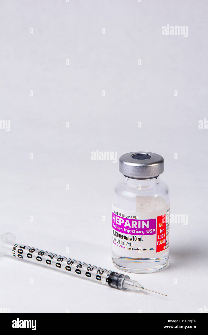 Un flacone di farmaco anticoagulante eparina sodica con una siringa su sfondo bianco Foto Stock