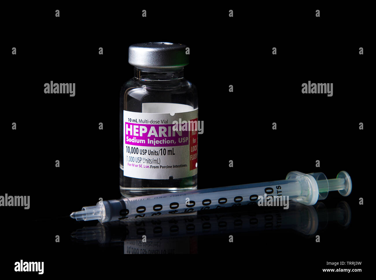 Un flacone di farmaco anticoagulante eparina sodica con una siringa su sfondo nero Foto Stock