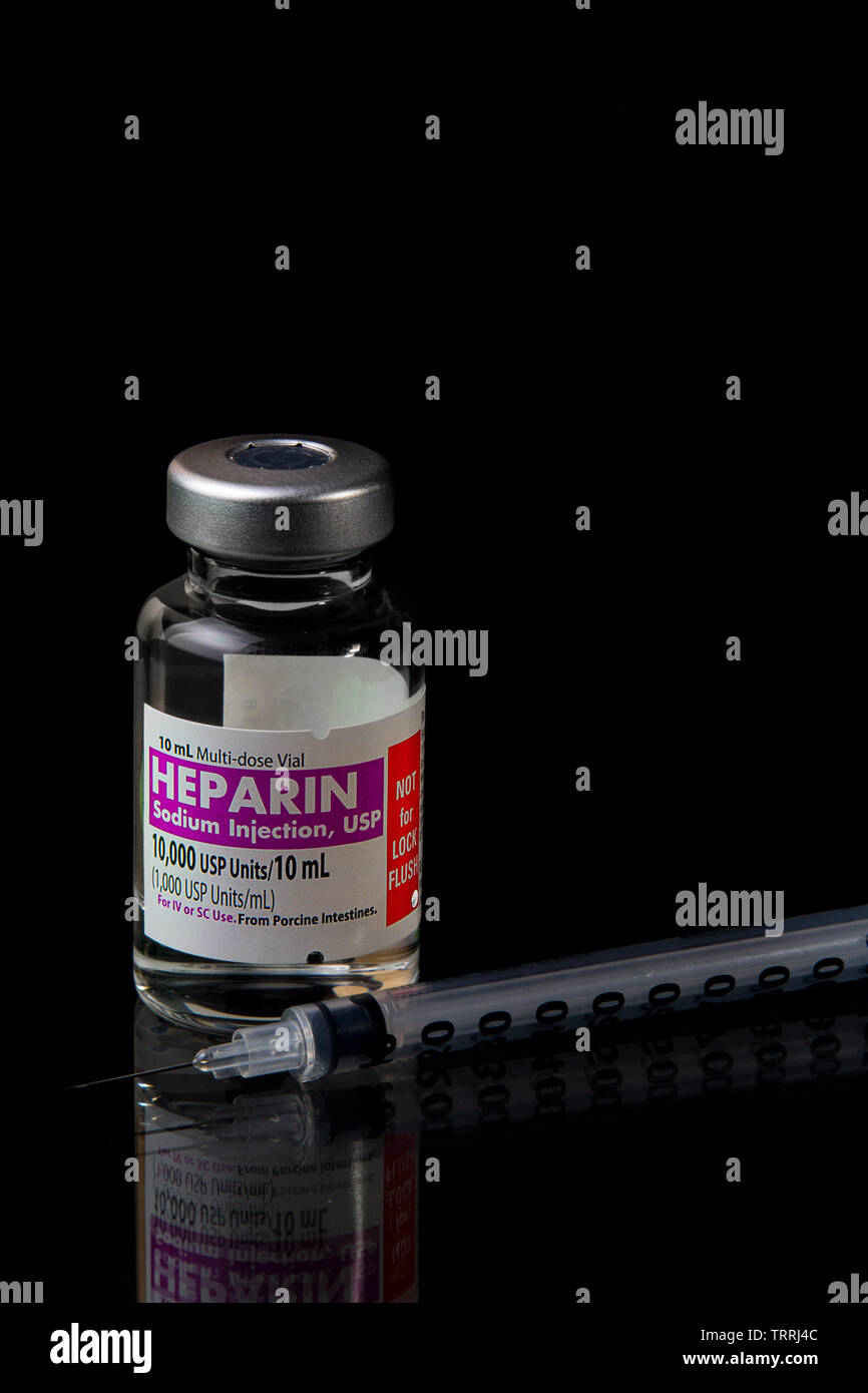 Un flacone di farmaco anticoagulante eparina sodica con una siringa su sfondo nero Foto Stock