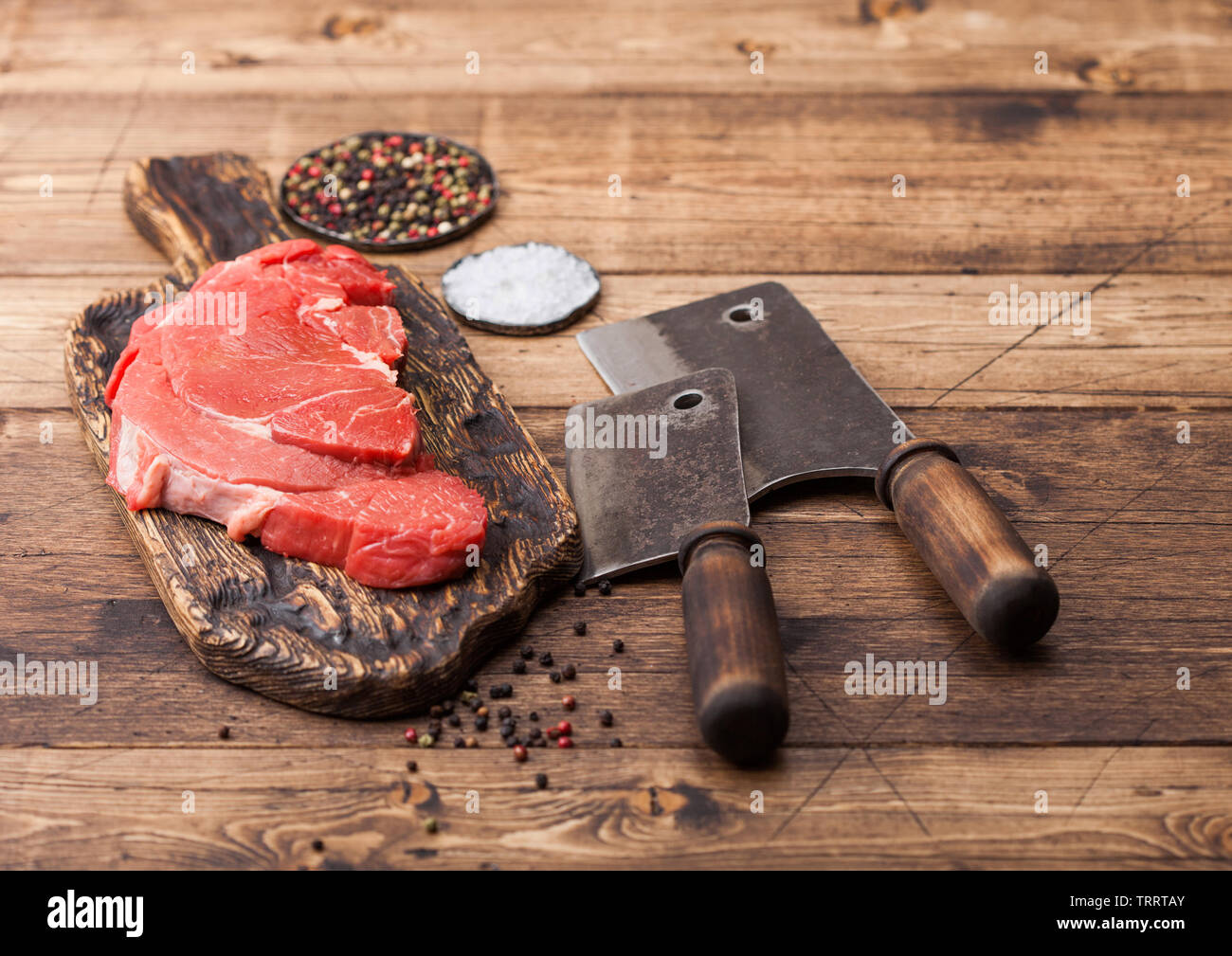 Crudo fresco dello strato organico di brasatura di filetto di manzo sul tagliere con carne asce su sfondo di legno. Foto Stock