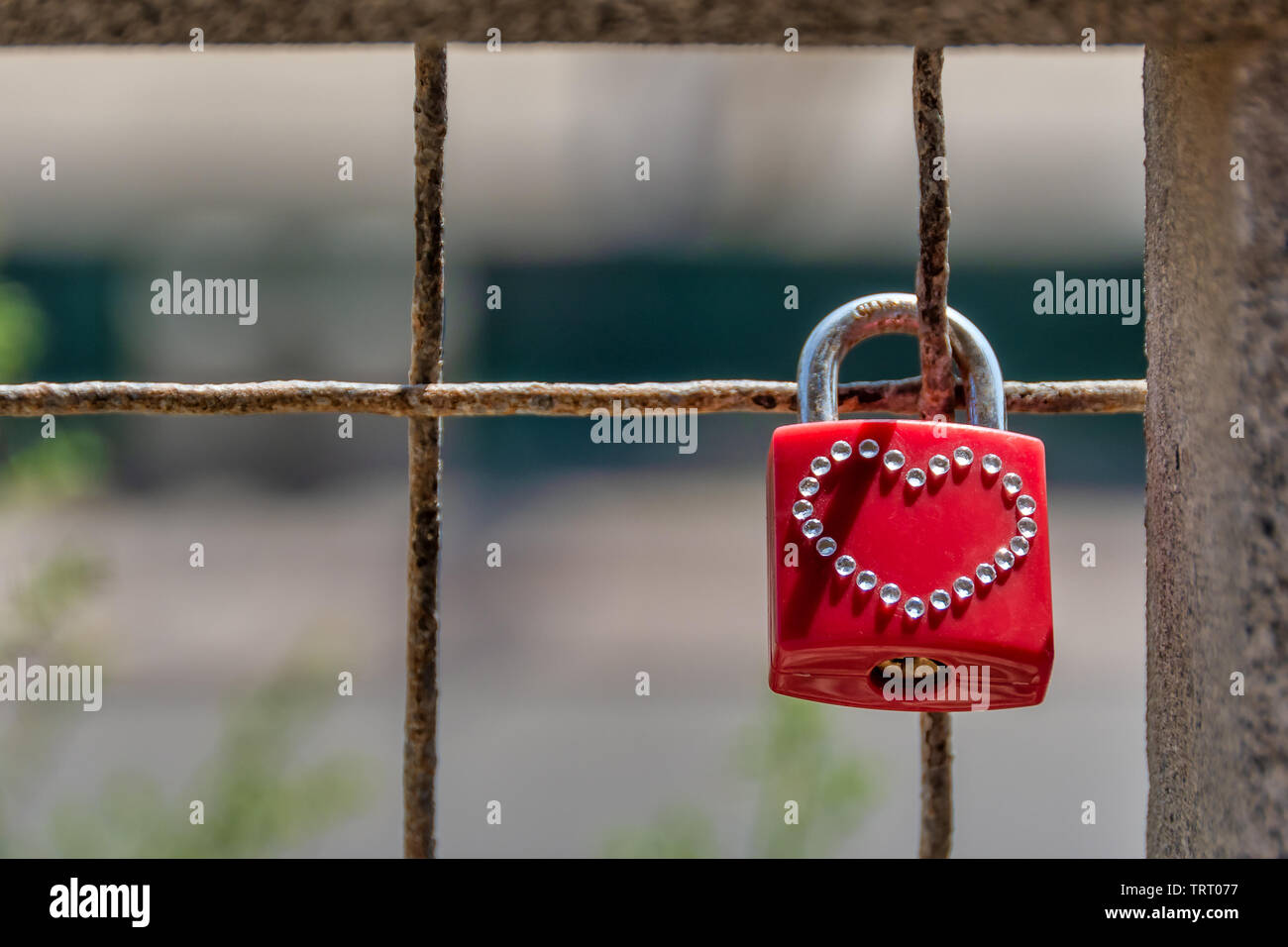 Lucchetto rosso con un hart forma realizzato in piccoli cristalli appesi bloccato sulla staccionata che simboleggia l'amore. Foto Stock