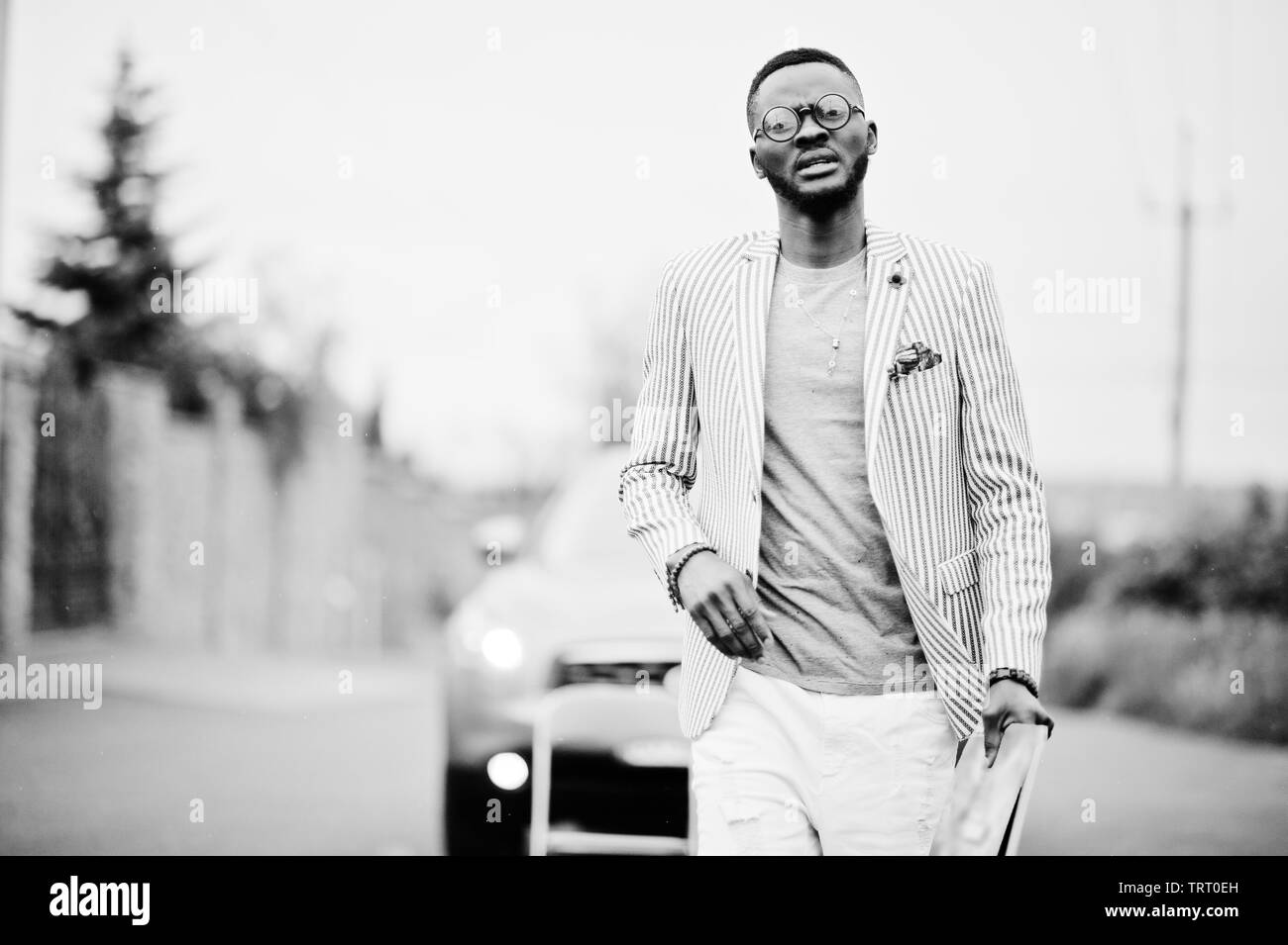 Ricca e di stile americano africano uomo in blazer e pantaloni bianchi,  occhiali con la rivista sul lato poste contro auto suv Foto stock - Alamy