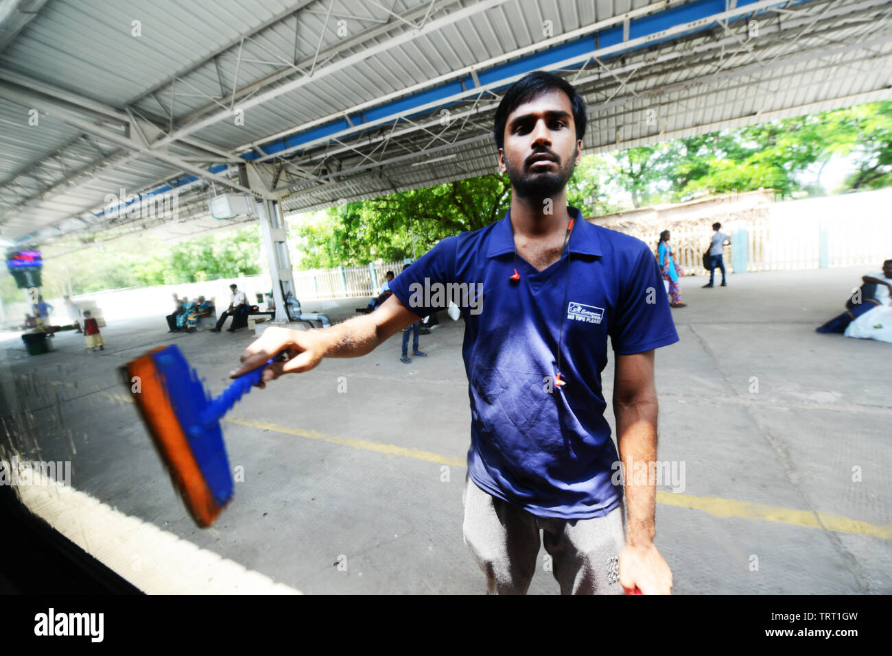 Un uomo che pulisce le finestre di un Indiano meridionale il treno. Foto Stock