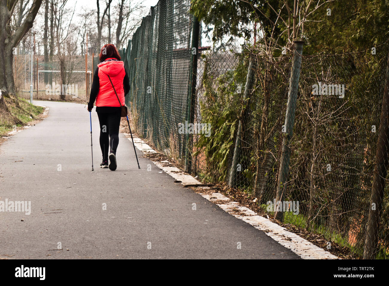 Donna facendo un Nordic walking lungo una strada Foto Stock