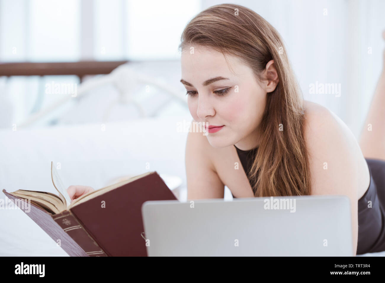 Bella ragazza adolescente leggendo un libro giaceva sul letto Foto Stock
