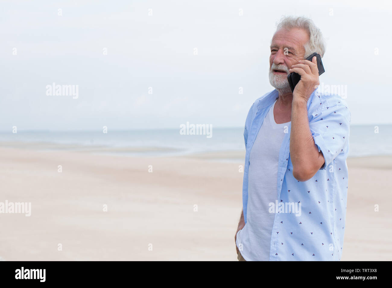 Senior singolo uomo che parla su chiamata durante la vacanza al mare spiaggia pulita spazio per il testo Foto Stock