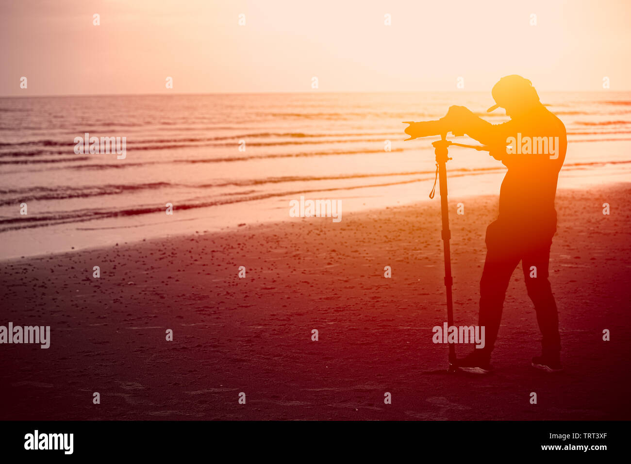 Silhouette di fotografo, uomo utilizzando monopiede fotografia in spiaggia Foto Stock