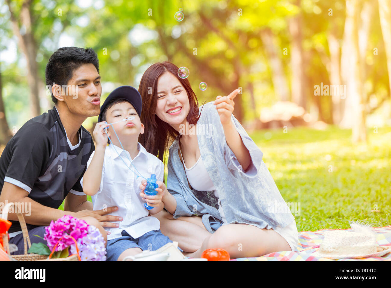 Famiglia asiatica si divertono bolla insieme nel verde del Parco Naturale di sfondo all'aperto Foto Stock