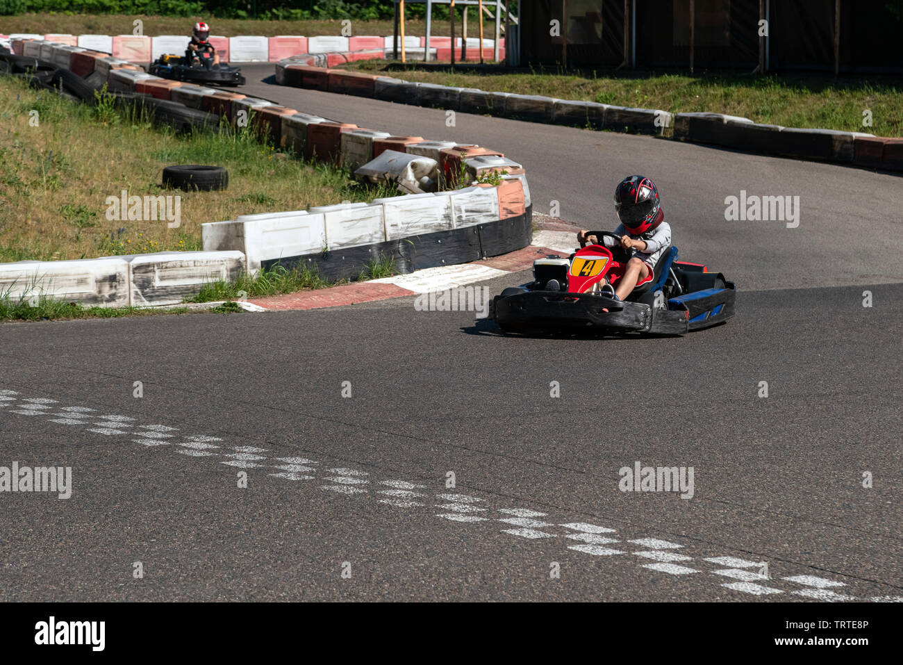 Giovane corridore in go-kart pista campionato di circuito che attraversa la linea di arrivo. Racer con un casco concorrenti sulla pista di karting, divertenti attività giovanili Foto Stock
