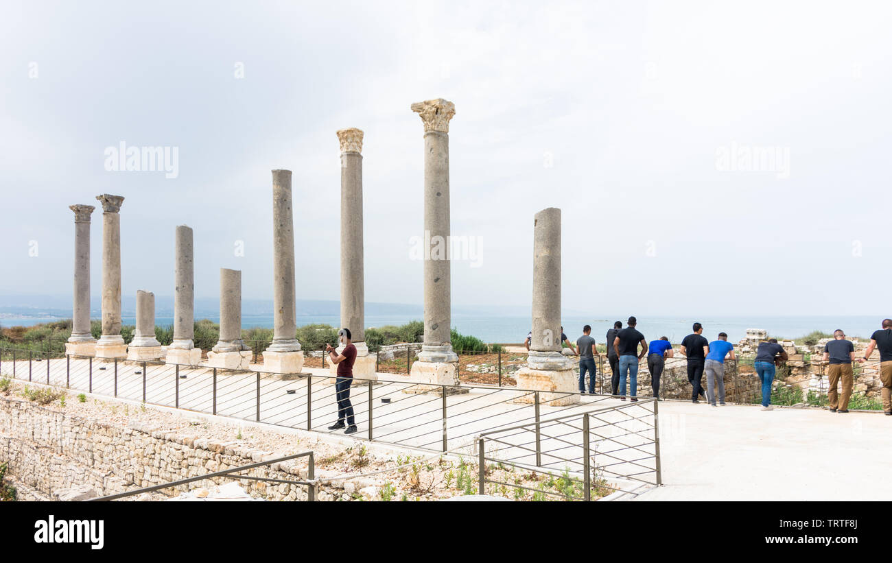 I turisti vicino a nove colonne di granito in Al Mina sito archeologico, pneumatico, Libano Foto Stock