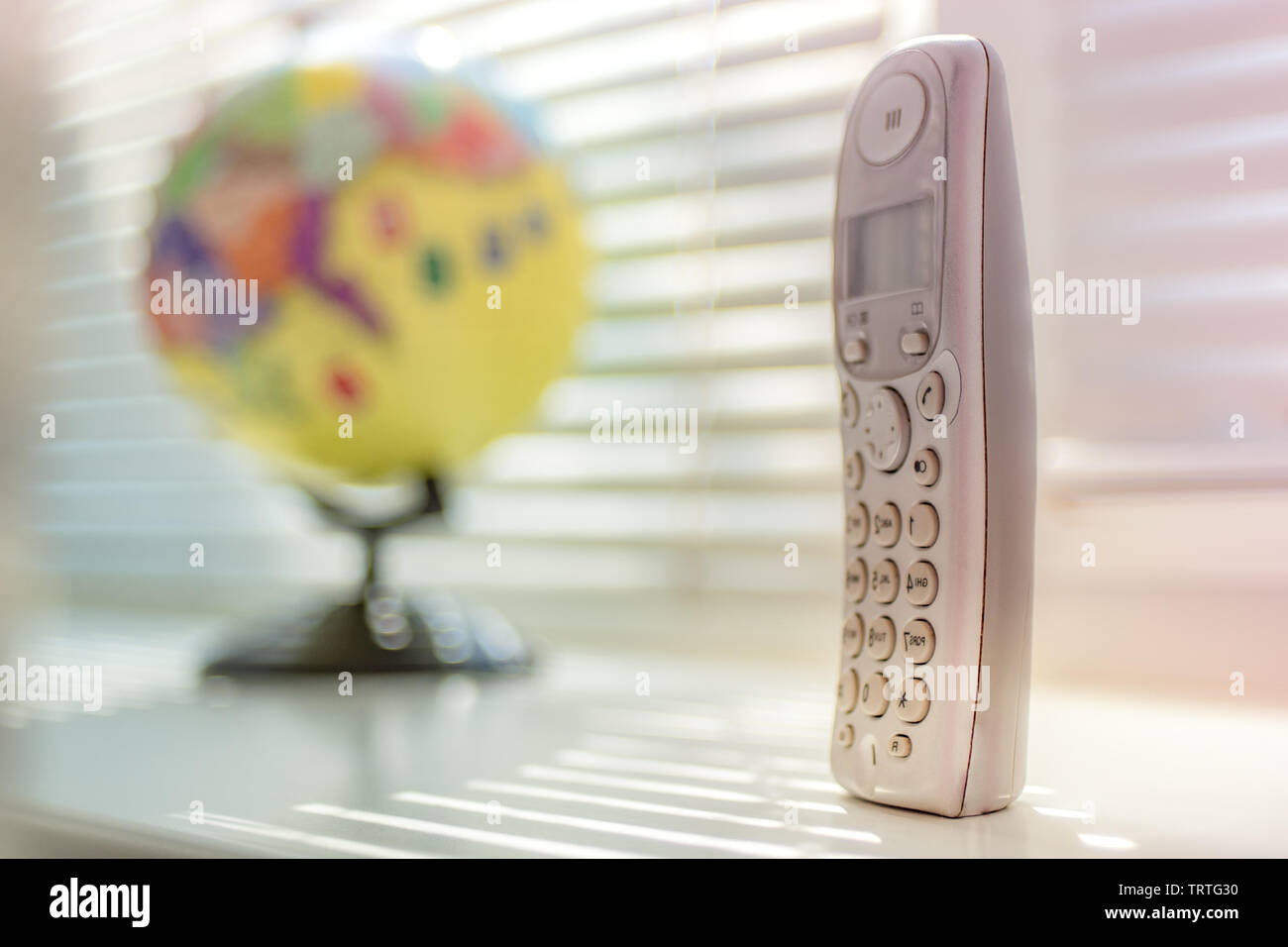 Ricevitore telefonico con pulsanti sullo sfondo del globo sul davanzale. Comunicazione globale concetto Foto Stock