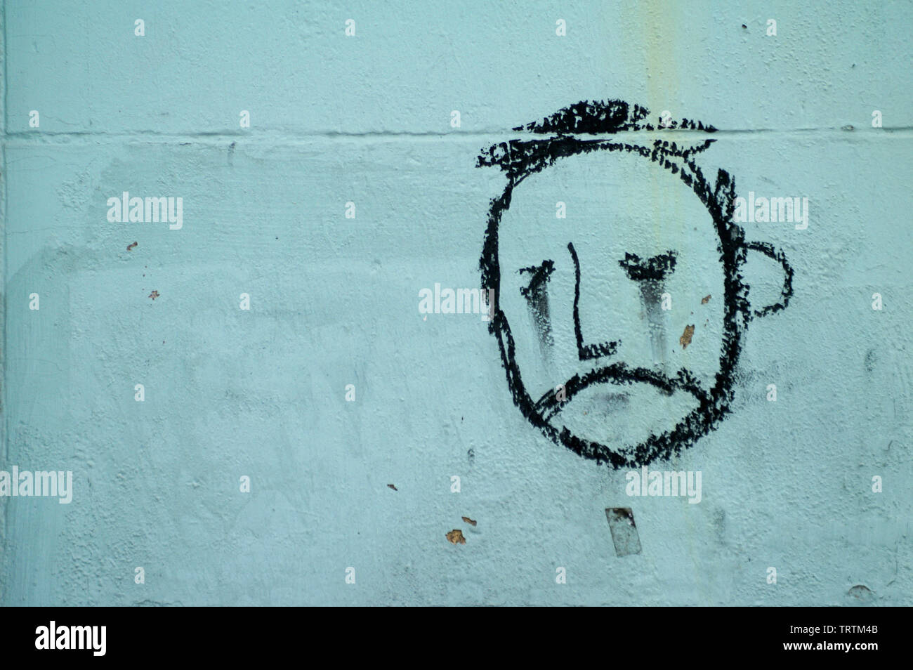 Graffiti, faccia di un triste guardando un uomo su un muro di Berlino, Germania Foto Stock