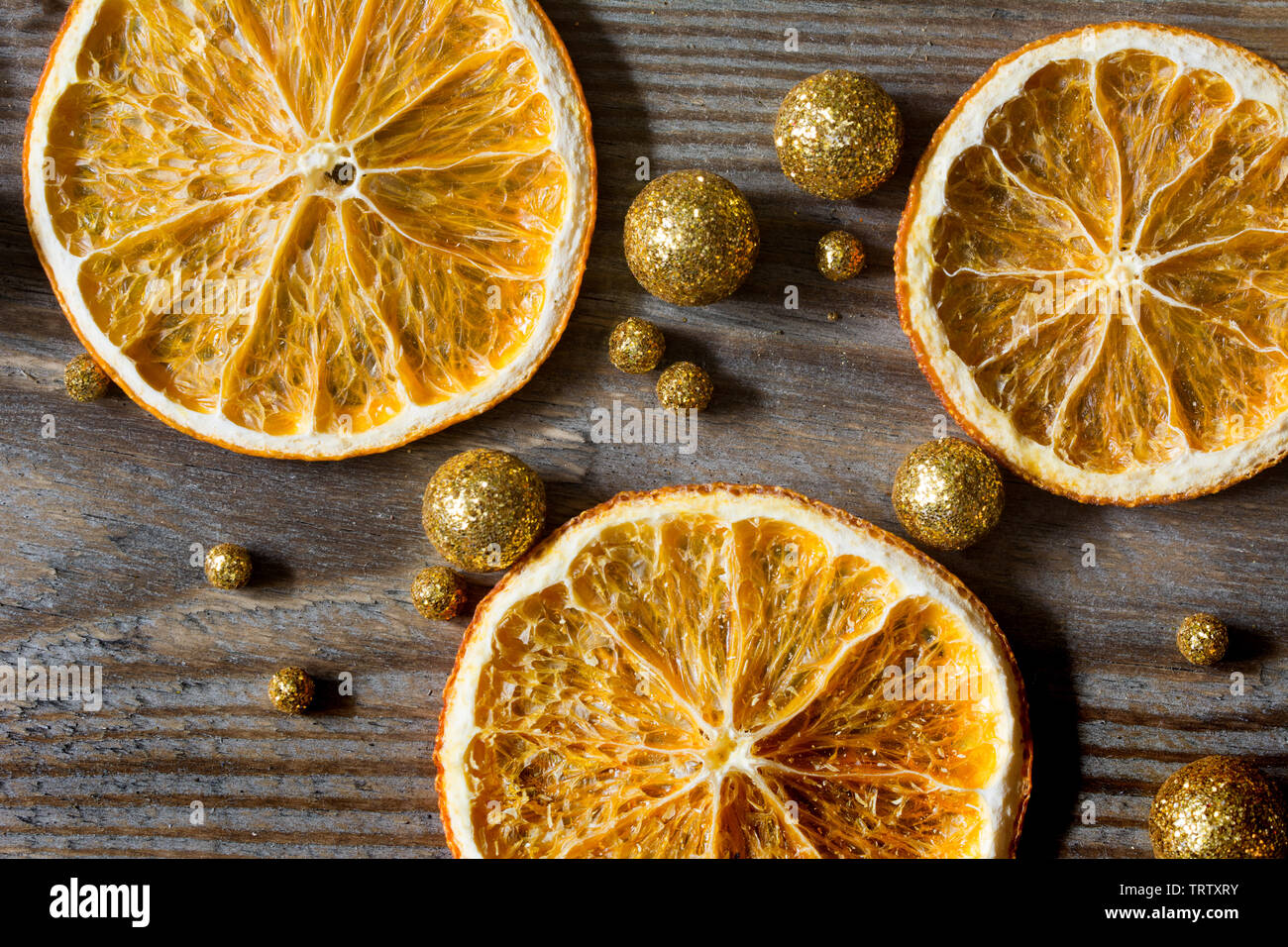 Composizione di natale con tre arance essiccate e golden glitter palle su sfondo di legno - close-up Foto Stock