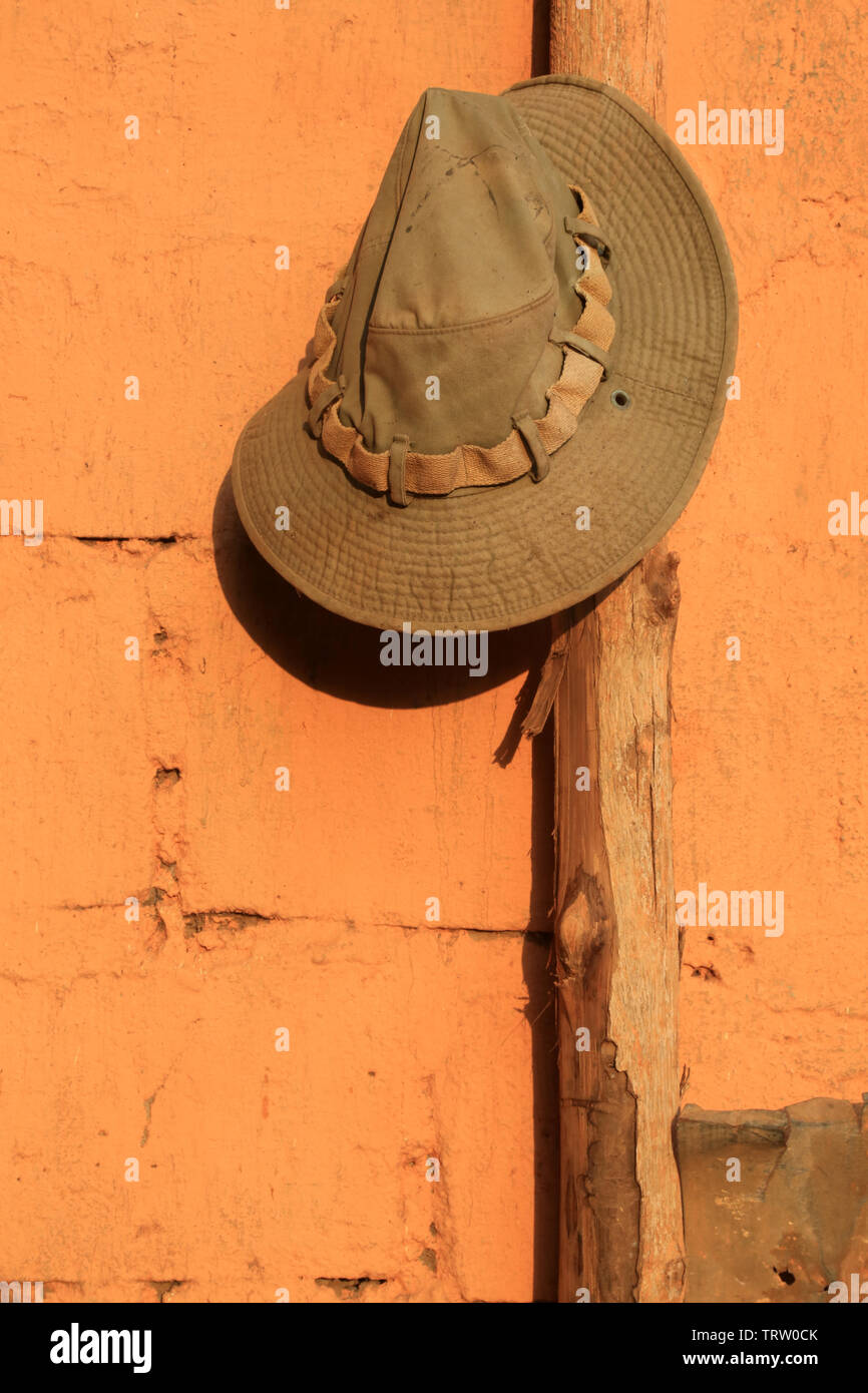 Chapeau en tissus suspendu sur un poteau en bois le long d'un mur. Togo. Afrique de l'Ouest. Foto Stock