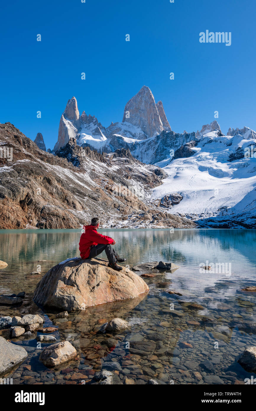 Un viandante sat ammirando la vista del monte Fitz Roy e Cerro Torre con Lago de los Tres, El Chalten, Patagonia, Argentina. Foto Stock