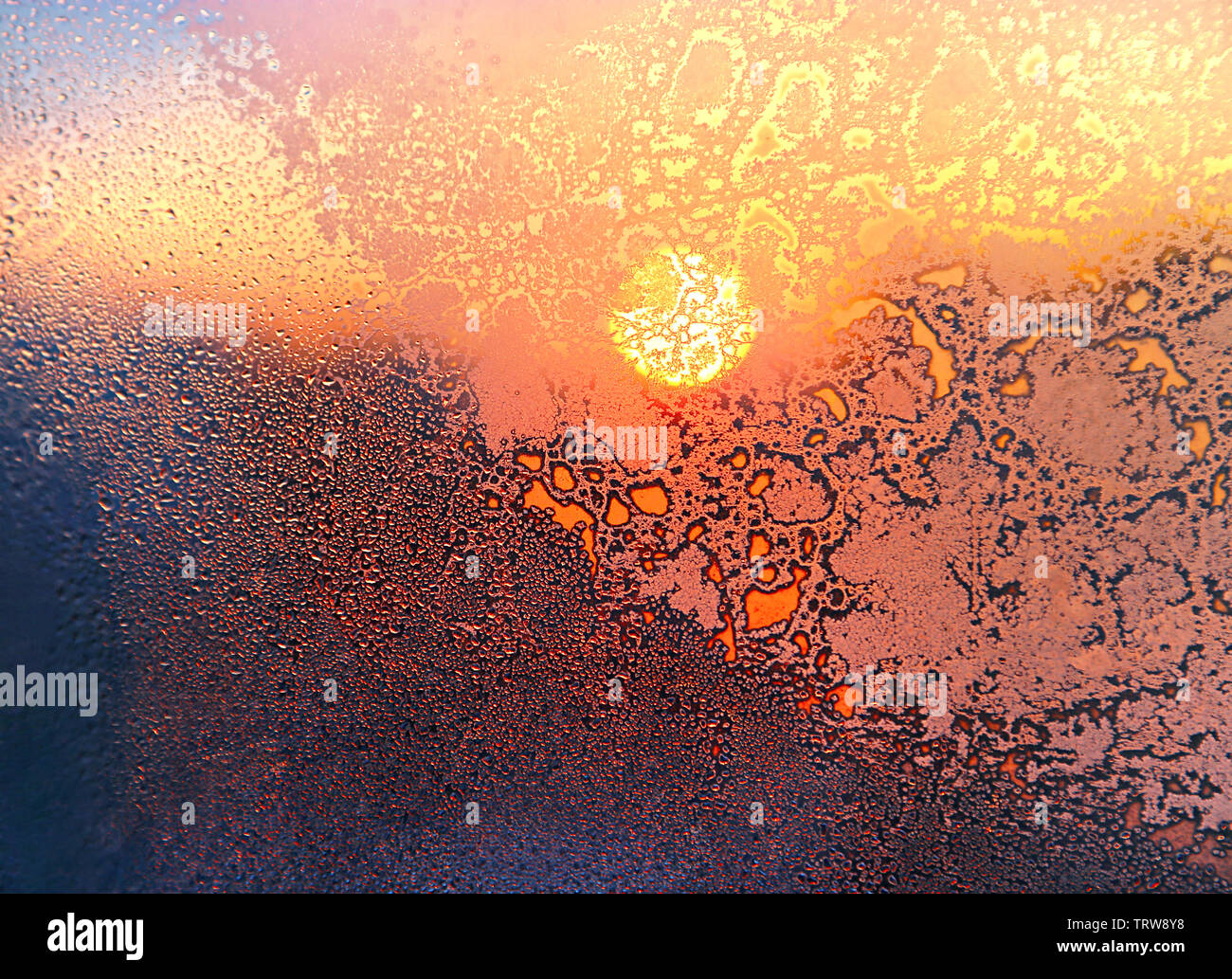 La natura dello sfondo con pattern di ghiaccio, la luminosa luce del sole e l'acqua scende in inverno vetro del finestrino Foto Stock