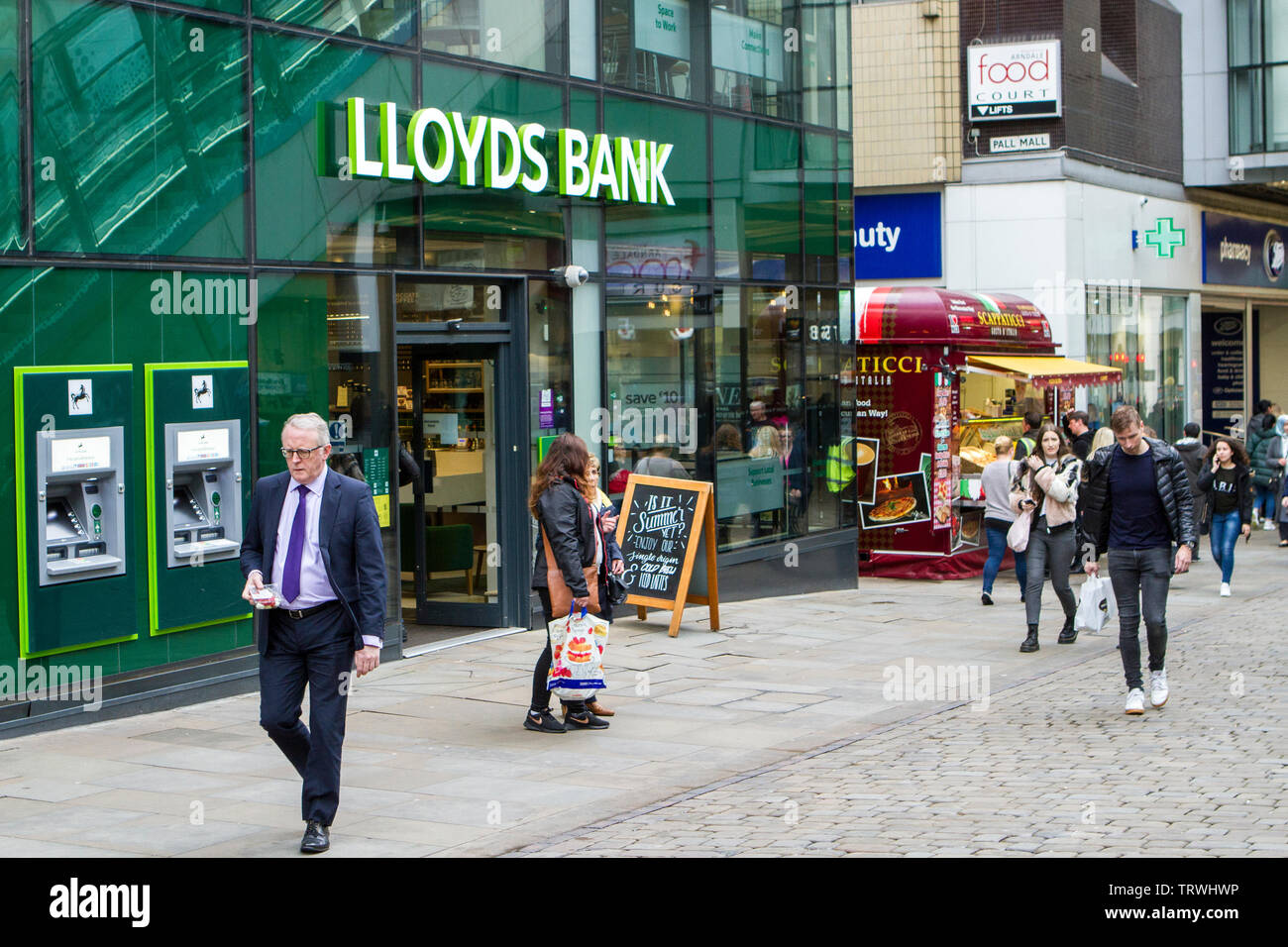 Persone di passaggio presso la Lloyds Bank nel centro della città di Manchester, Regno Unito Foto Stock