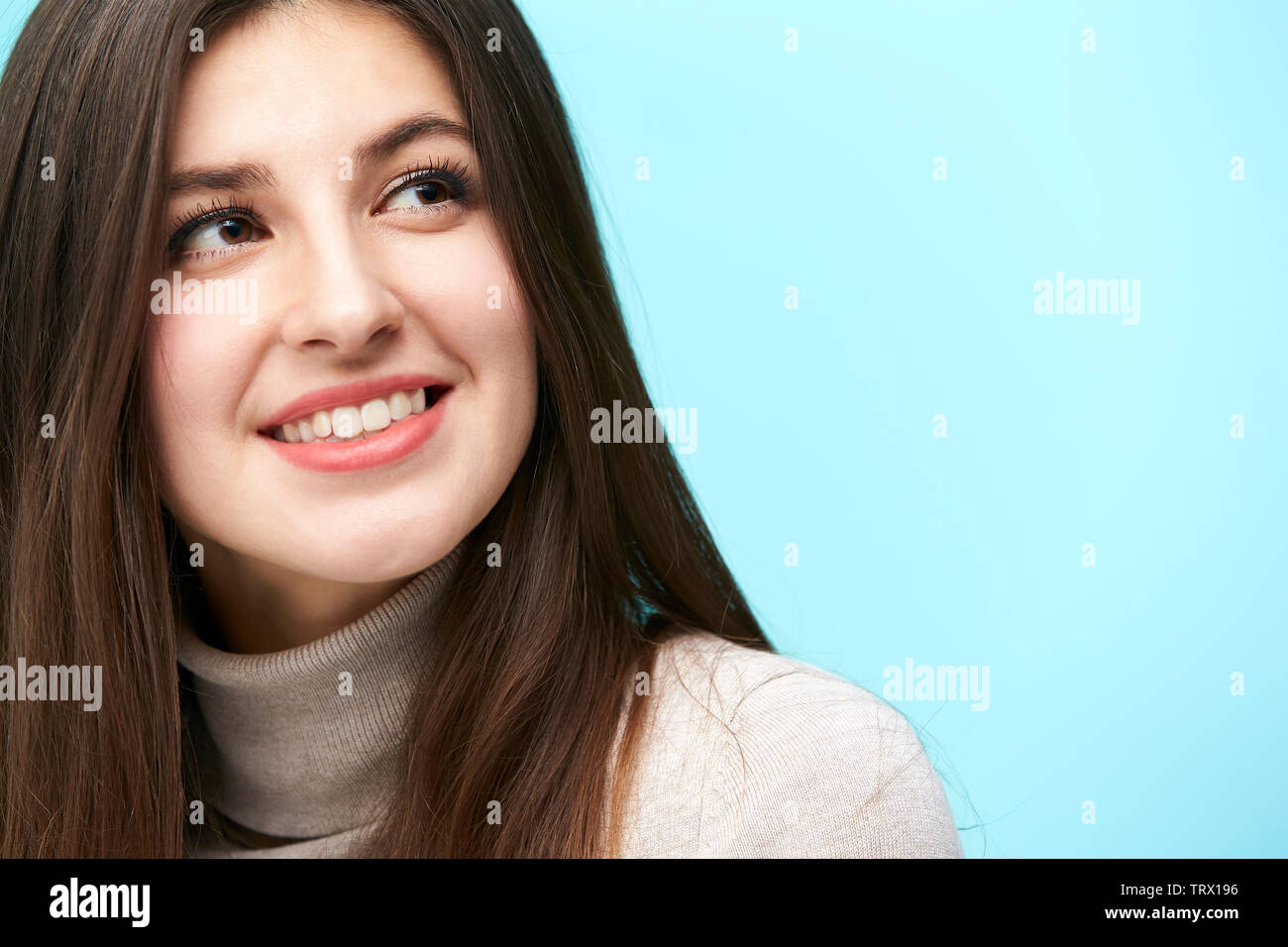 Testa e la spalla ritratto di una giovane donna caucasica isolata su sfondo blu Foto Stock