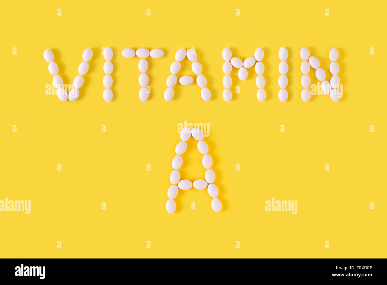 La vitamina A pillole sceso dalla bottiglia su sfondo giallo. Appartamento laico, vista dall'alto, copia gratuita dello spazio. Foto Stock