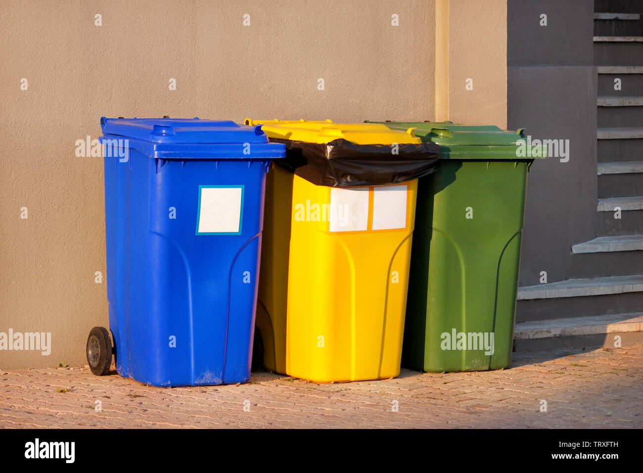 Cestino, spazzatura, contenitore di riciclaggio nel complesso turistico  balneare, in attesa di essere prelevato dal camion della spazzatura. Blu,  giallo e verde di contenitori per rifiuti Foto stock - Alamy