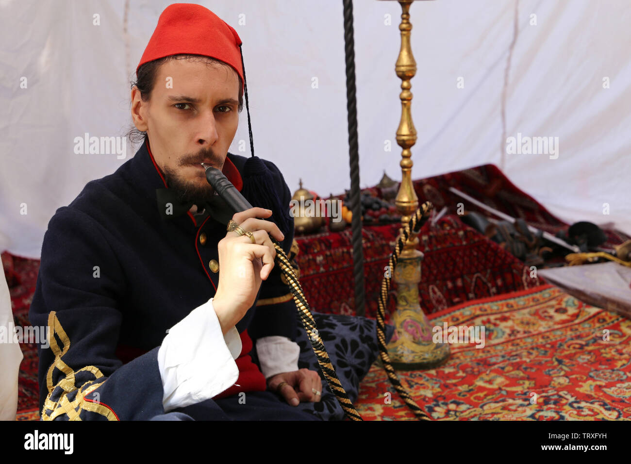 Bagno turco uomo fuma un narghilè seduti sul tappeto in una tenda durante la mosca festival storici tempi e epoche. La vita nell'impero ottomano Foto Stock