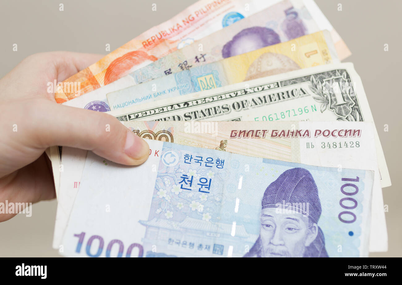 Una mano che tiene il denaro banconote di paesi diversi: won coreano, rublo russo, dollaro USA, Cinese yuan RMB e ucraina grivna Foto Stock