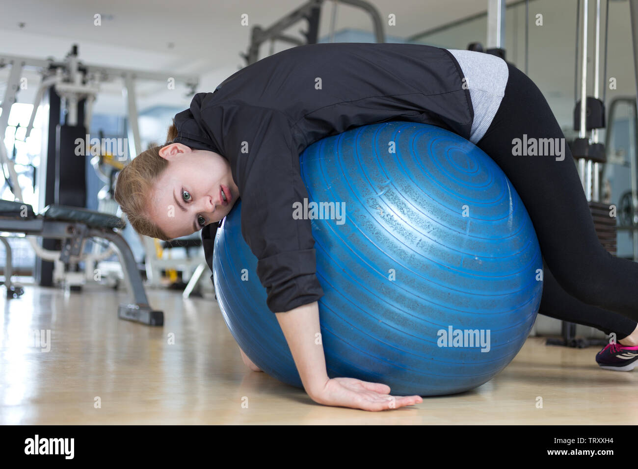 Giovane donna caucasica giacente sul blu palla ginnica cercando esaurito, stanco, annoiato e stanco in palestra Foto Stock