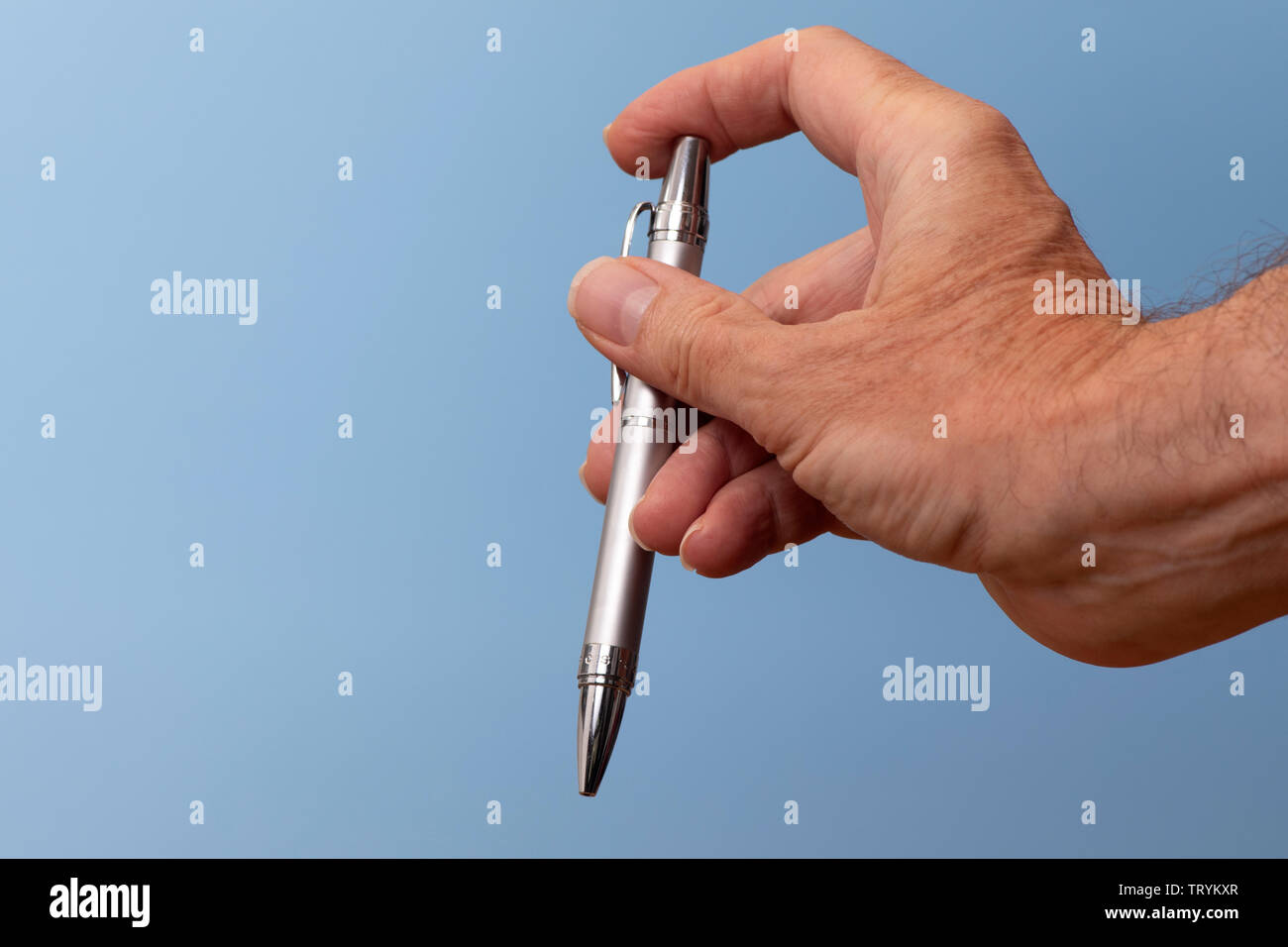 Argento Satinato penna a sfera in una mano mans, facendo clic su on e off. Foto Stock