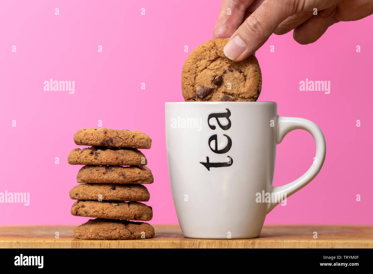 Dunking un biscotto in una tazza di tè, biscotti con scaglie di cioccolato. Foto Stock