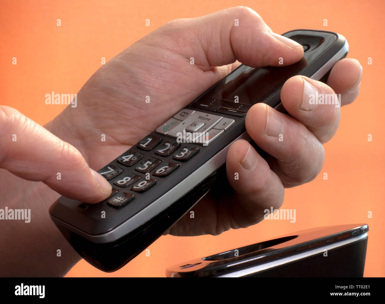 Mano d'uomo tenendo un vivavoce del telefono di rete fissa premendo un numero sul tastierino per effettuare una chiamata. Foto Stock