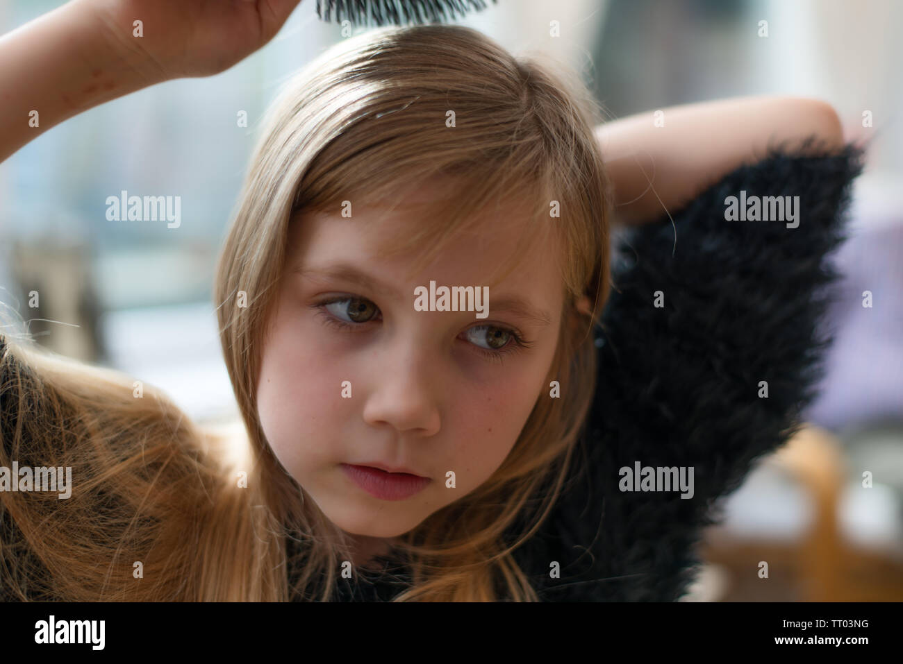 Giovane ragazza carina spazzolando i suoi lunghi capelli in morbido dreamy focus Foto Stock
