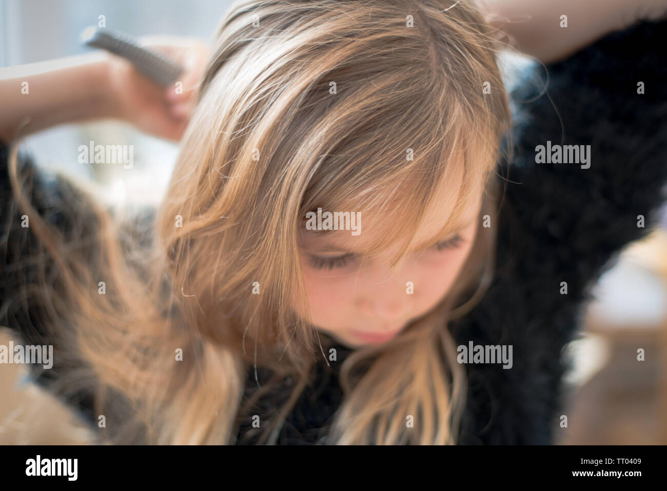 Giovane ragazza carina spazzolando i suoi lunghi capelli in morbido dreamy focus Foto Stock