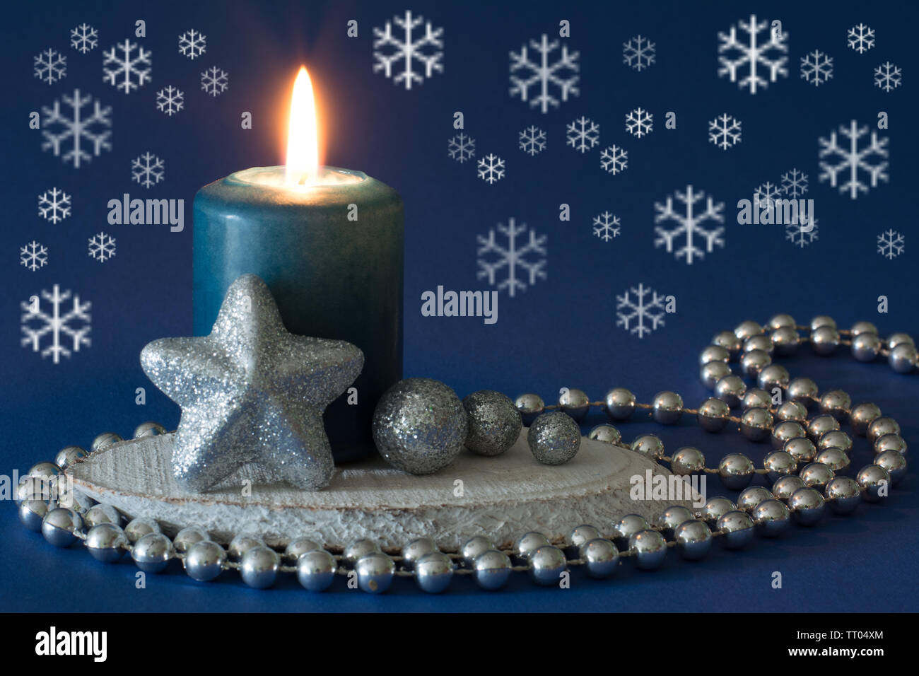 Argento e blu composizione di natale con candela che brucia, glitter star, globuli, fiocchi di neve e la catena del tallone su sfondo blu scuro Foto Stock