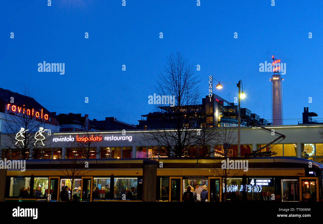 HELSINKI, Finlandia - 6 April 2019: il tram passa per auto di luci al neon e ristorante Ravintola nel complesso Lasipalatsi, ora anche Amos Rex galleria d'arte. Foto Stock