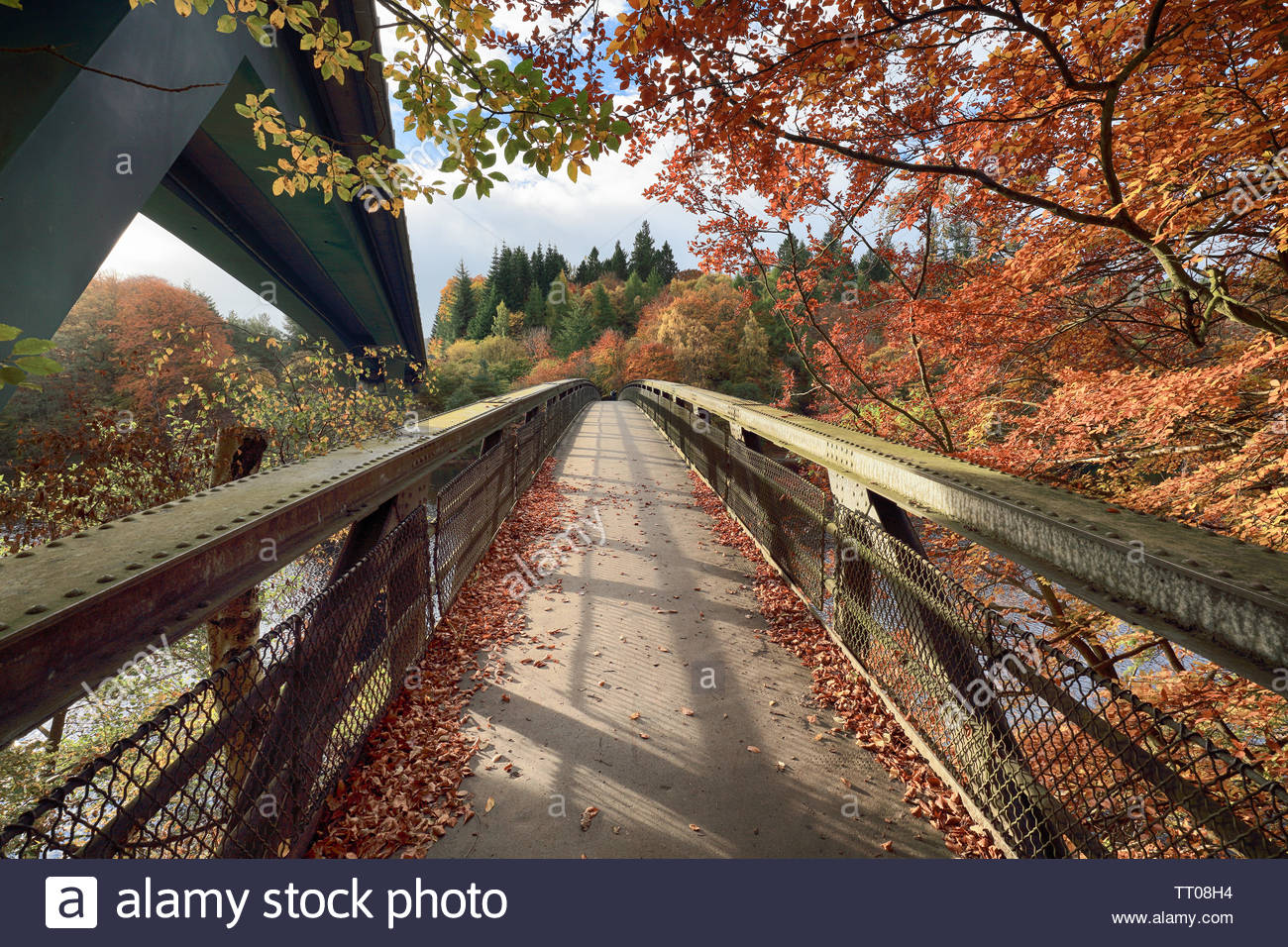 Una passerella che va oltre il Loch Faskally in Perthshire con l'autunno alberi appesa sopra il ponte. Foto Stock