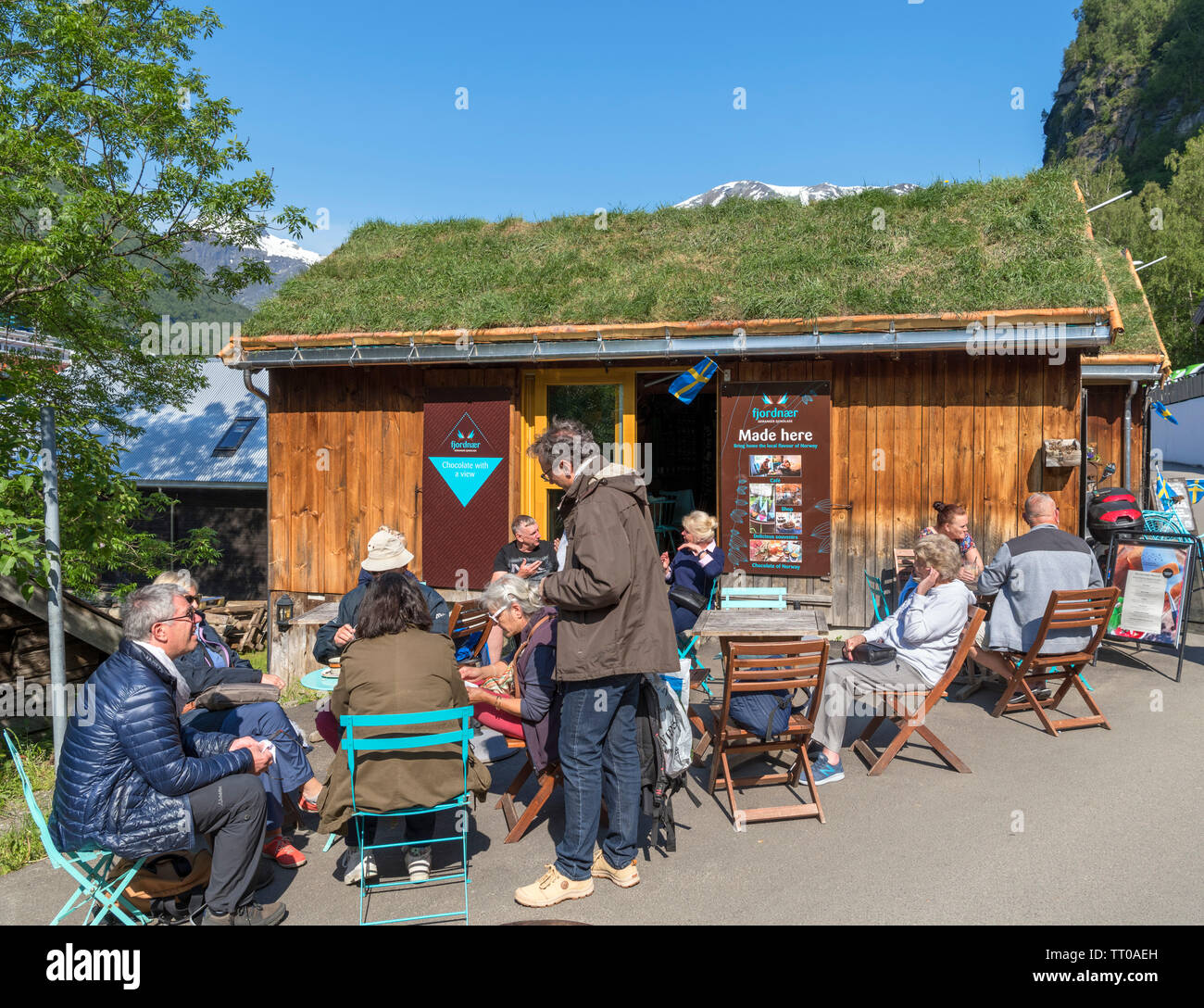 La gente seduta al di fuori di una caffetteria specializzata nella cioccolata calda, Geiranger, Møre og Romsdal, Sunnmøre, Norvegia Foto Stock