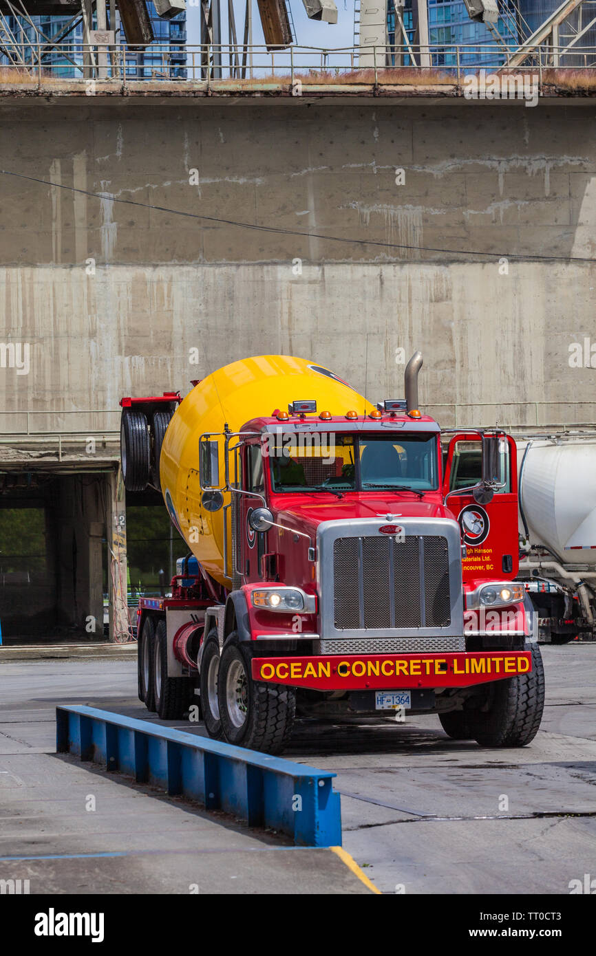 Rosso e giallo redi-mix concrete carrello lasciando l'Oceano deposito di cemento su Granville Island in Vancouver British Columbia Foto Stock