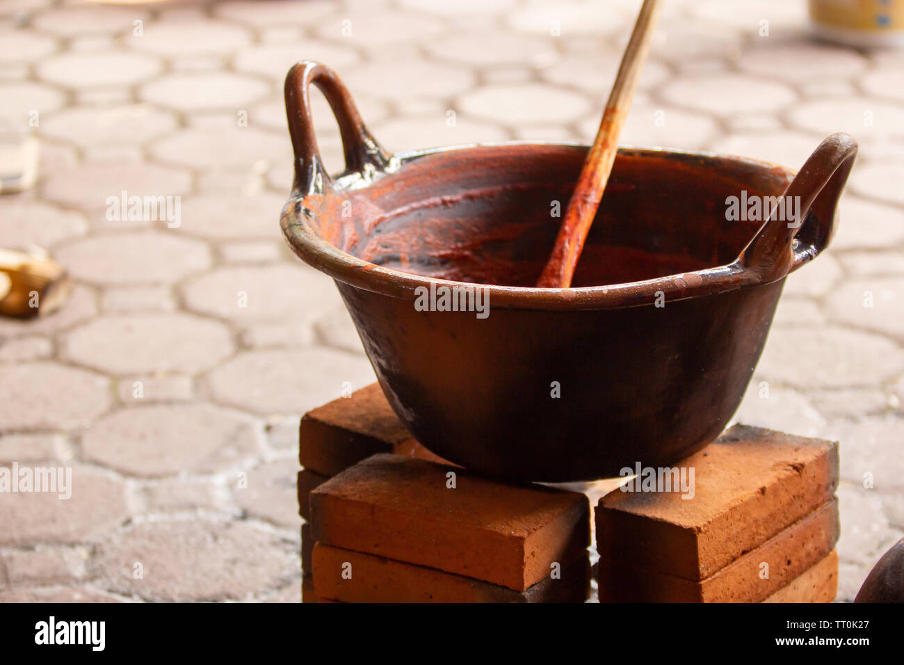 Un messicano fatto a mano pentola di creta con mole su una pietra tre sparò stufa a legna Foto Stock