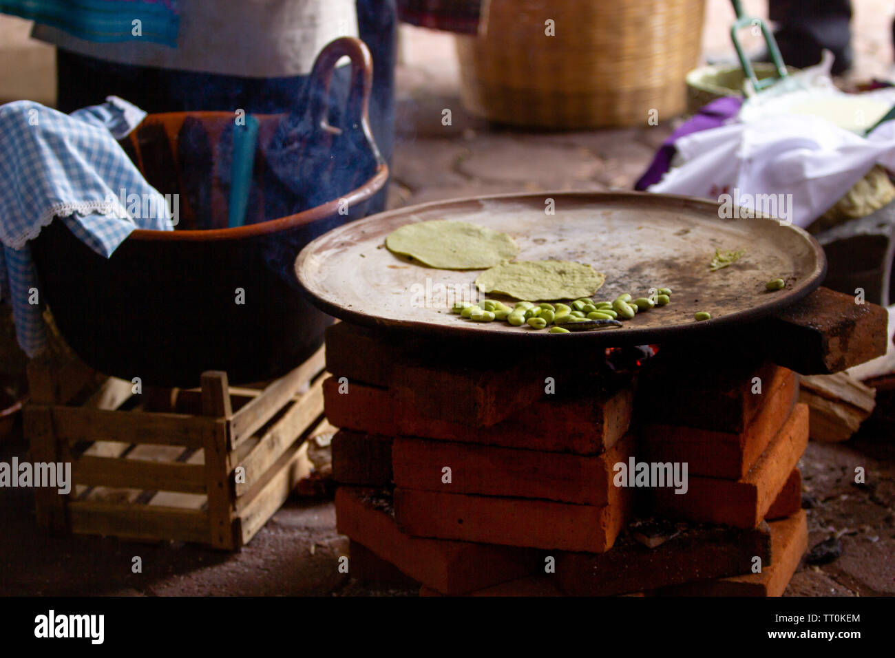 Tortilla di cottura su un messicano tre pietre sparò stufa a legna, mole e fave, rurale scena Foto Stock