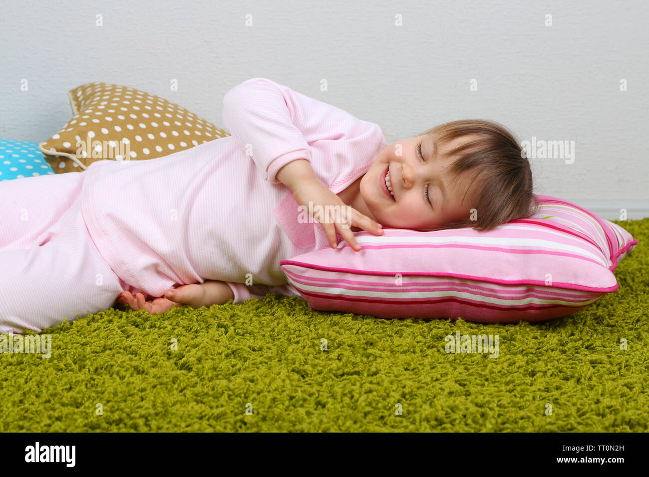 Bambina giacente sulla moquette in camera Foto Stock