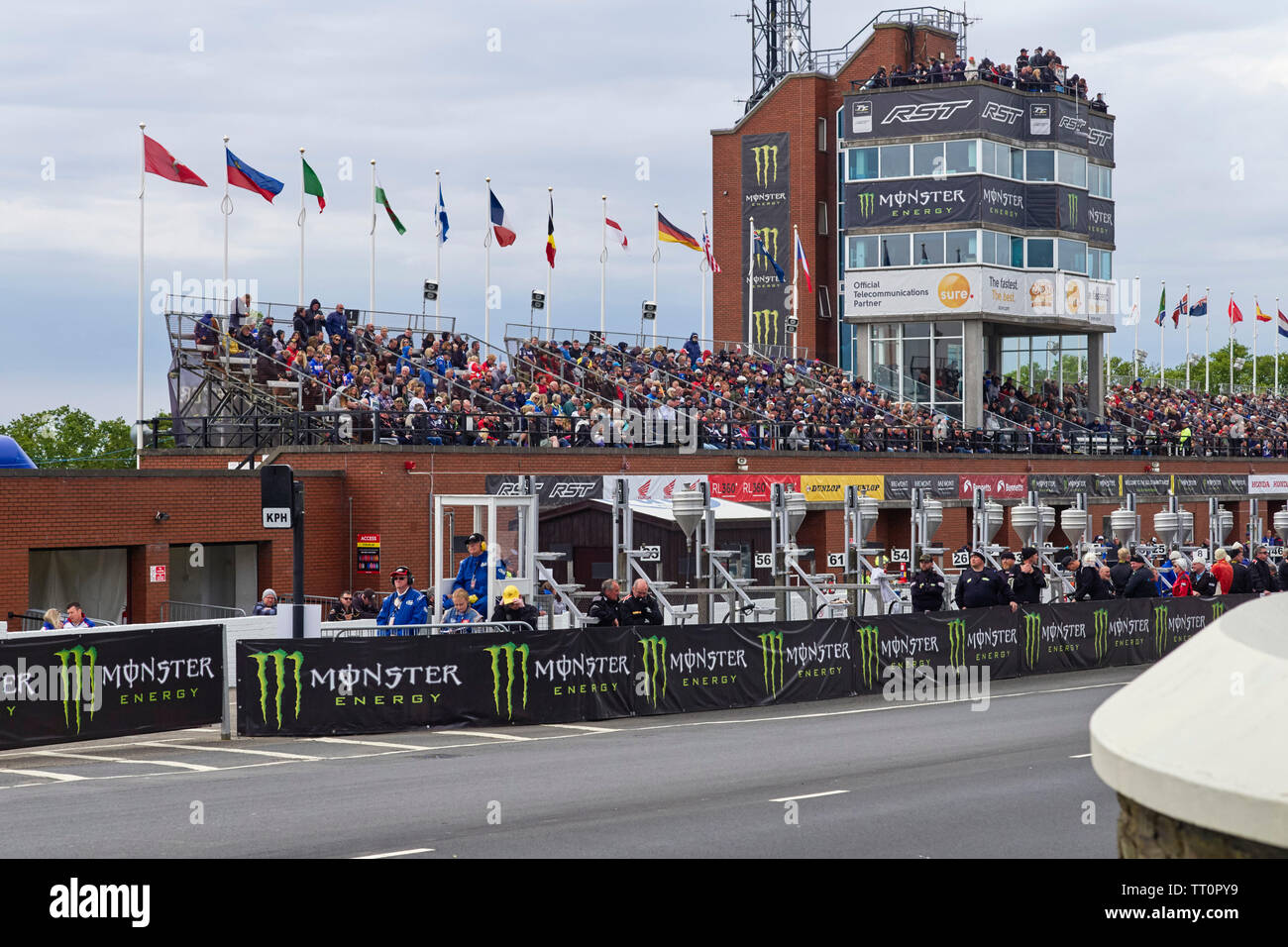 La tribuna durante il senior TT gare dove gli spettatori attendere per biciclette ad apparire lungo con pit lane meccanica Foto Stock