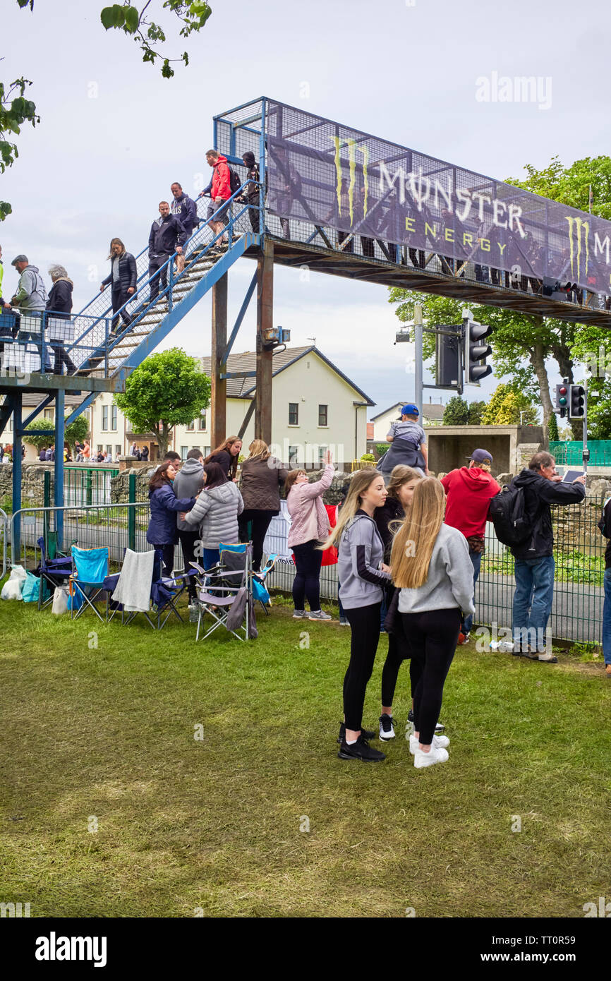 Gara watchers tornando alla tribuna principale area via la passerella alla fine del 2019 gare TT mentre le strade sono ancora chiuse Foto Stock