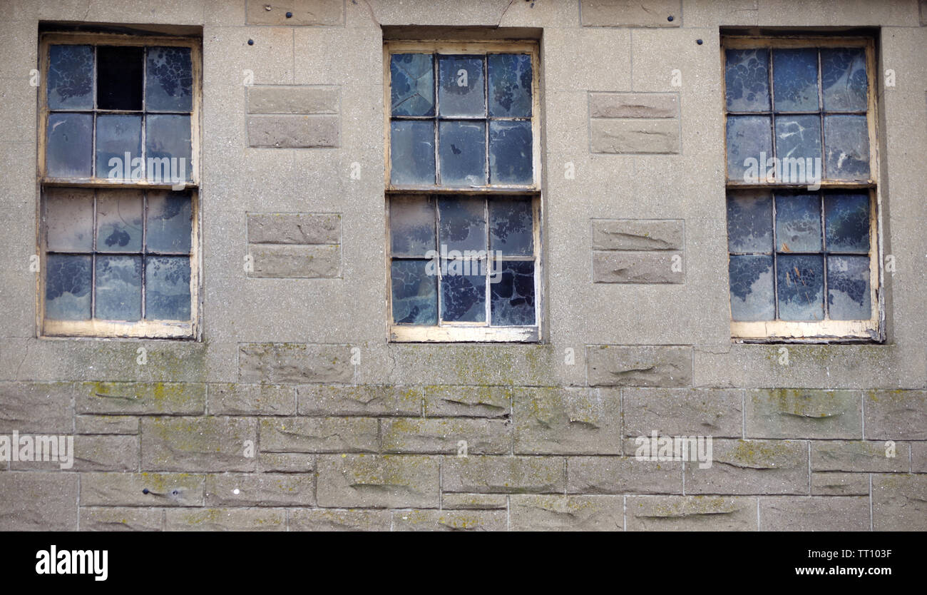 Sporche finestre a ghigliottina sopra un negozio di Dunbar High Street, East Lothian, Scozia Foto Stock