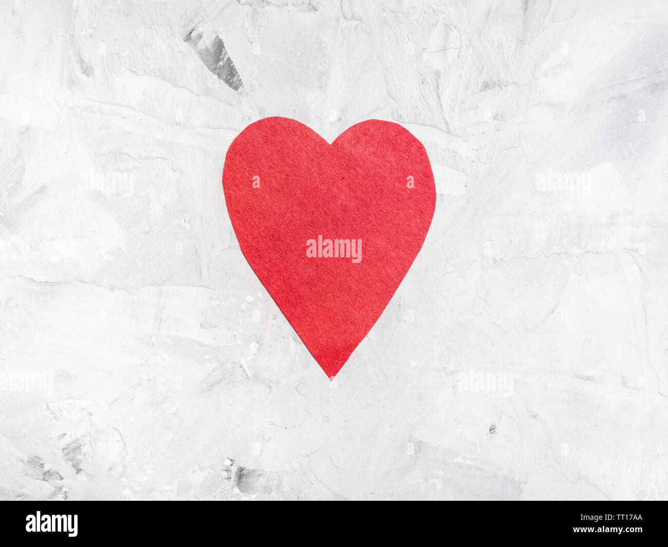 Un cuore tagliata dalla carta rossa sul cemento grigio board Foto Stock