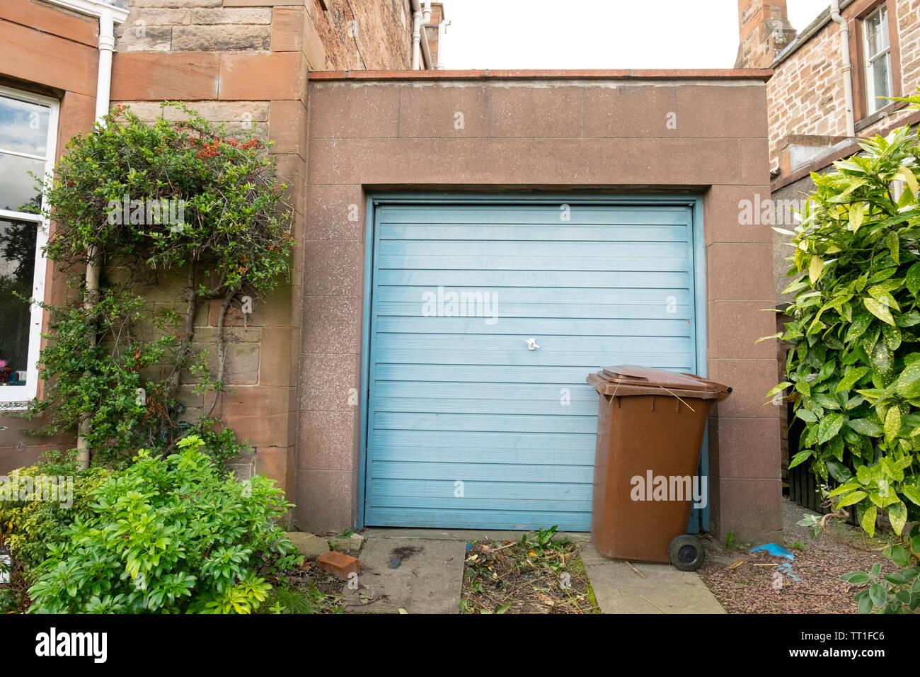 Blue porta di garage e brown wheeliebin bidone dei rifiuti da casa nel quartiere vittoriano di Morningside, Edimburgo, Scozia, Regno Unito Foto Stock