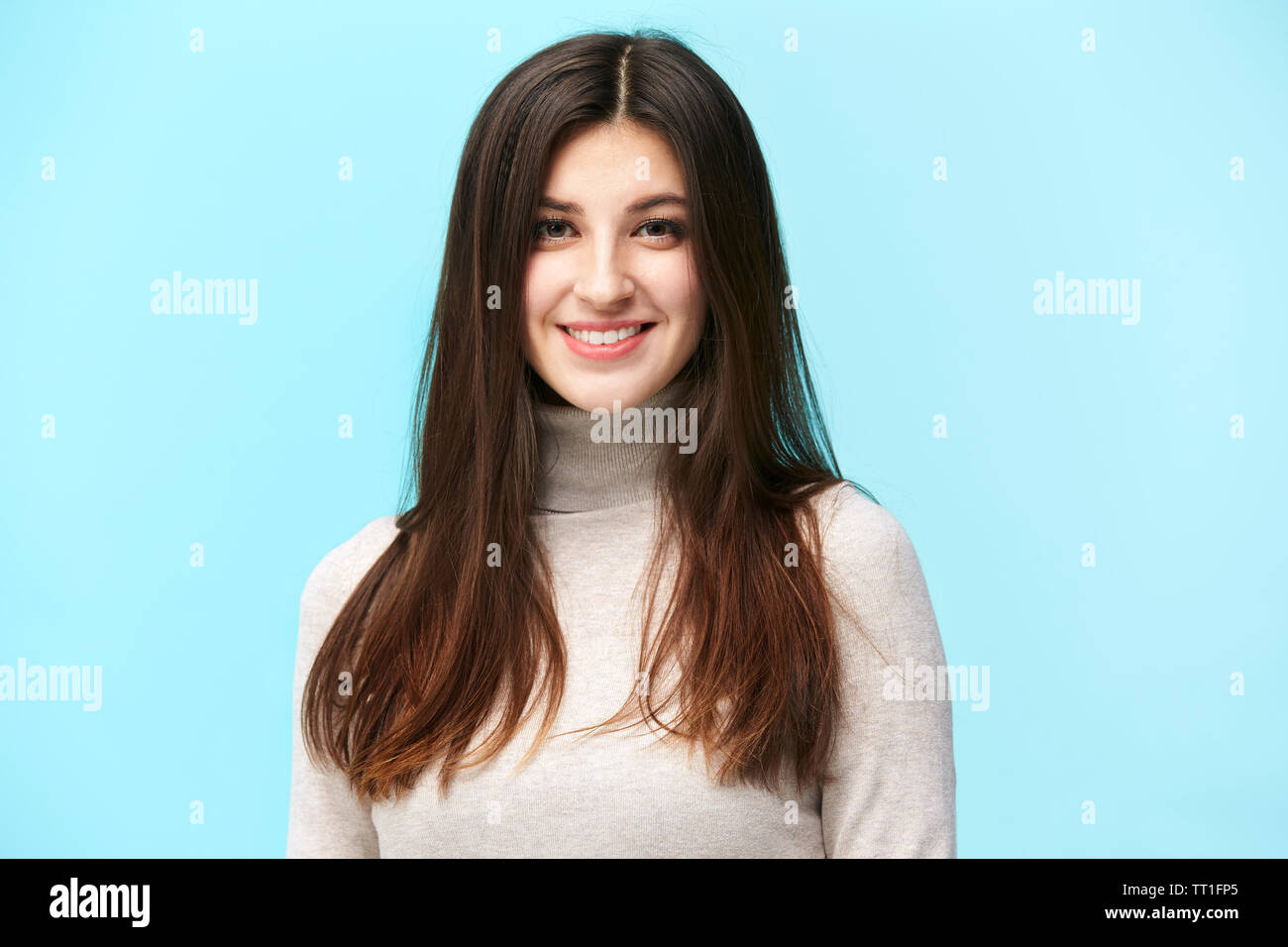 Ritratto di una giovane e bella donna caucasica, felice e sorridente, guardando la telecamera, isolato su sfondo blu Foto Stock