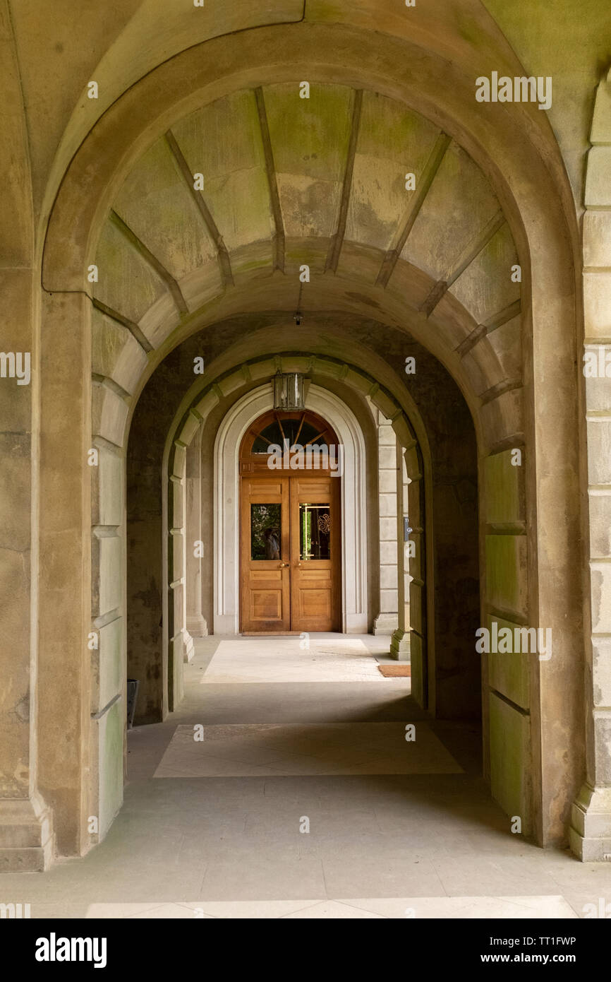 Antica pietra passerella ad arco che conduce a porta chiusa alla fine, alla storica Cliveden House, England, Regno Unito Foto Stock