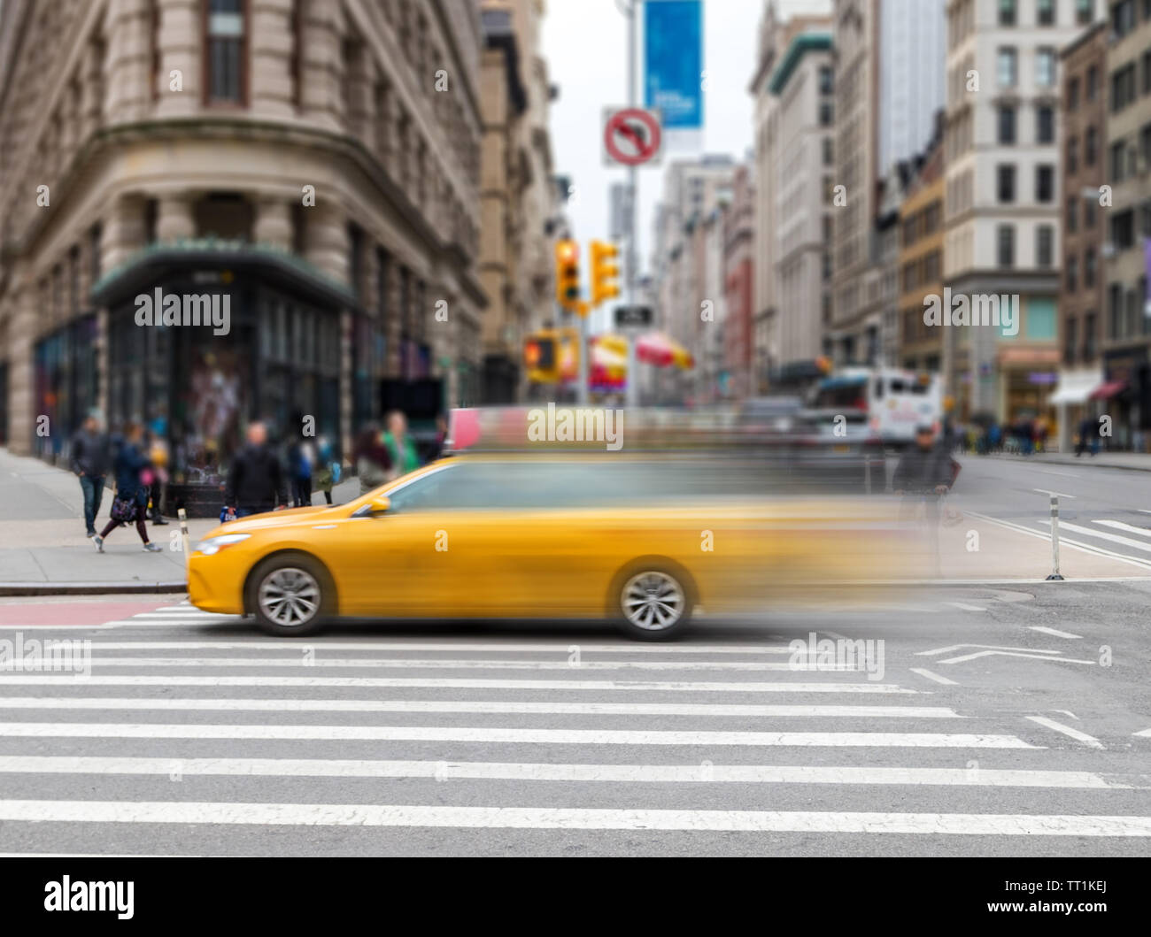 Motion Blur di giallo taxi accelerando attraverso un'intersezione sulla 23rd Street in Midtown Manhattan New York City NYC Foto Stock