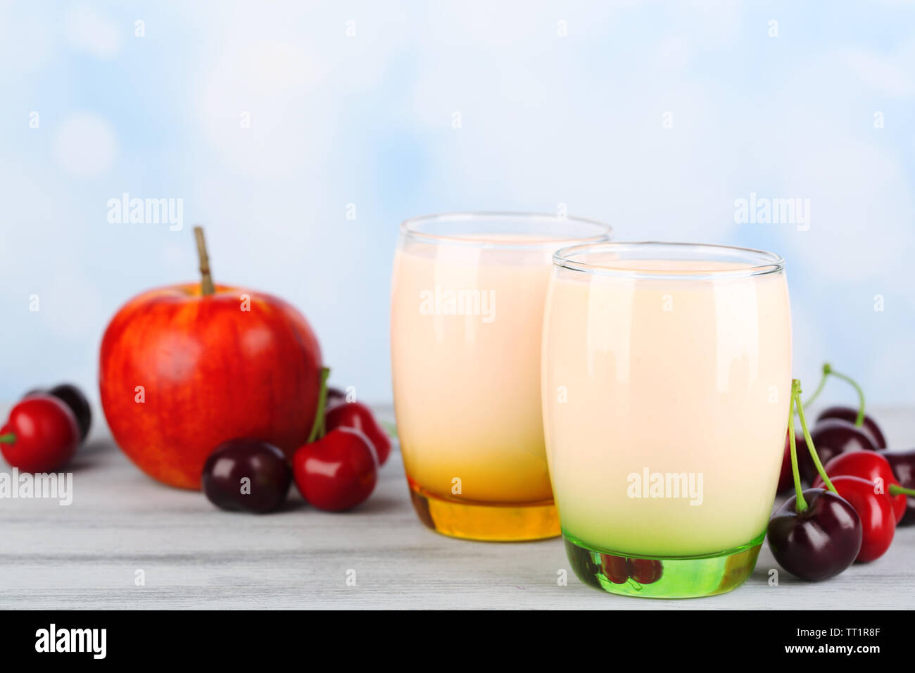 Delizioso yogurt con frutta gusti in bicchieri e frutta fresca sul tovagliolo, sul colore tavolo in legno, su sfondo chiaro Foto Stock